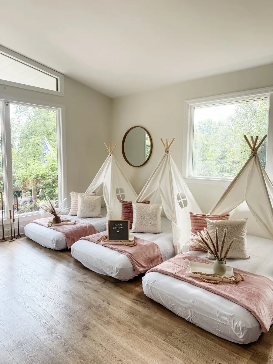 Boho teepee sleepover setup with white teepees, dusty-rose velvet blankets, neutral pillows, and pampas grass in a bright Central PA home
